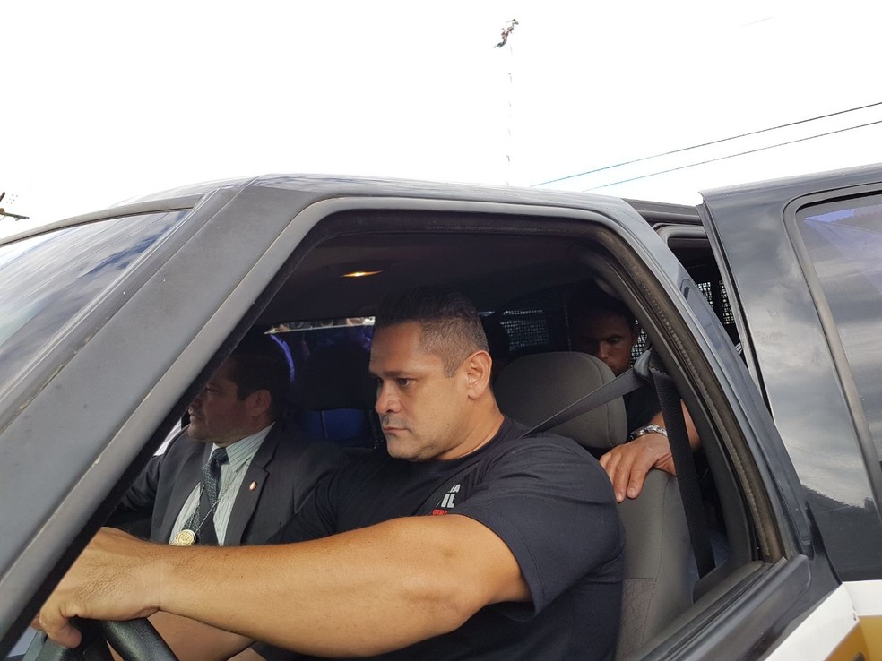 No banco de trás da viatura da polícia, Bruno chega ao presídio de Varginha (Foto: Samantha Silva / G1)