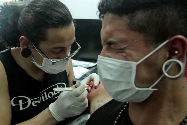 Artista molda o desenho na carne de viva. (Foto: Juan Cevallos/AFP)