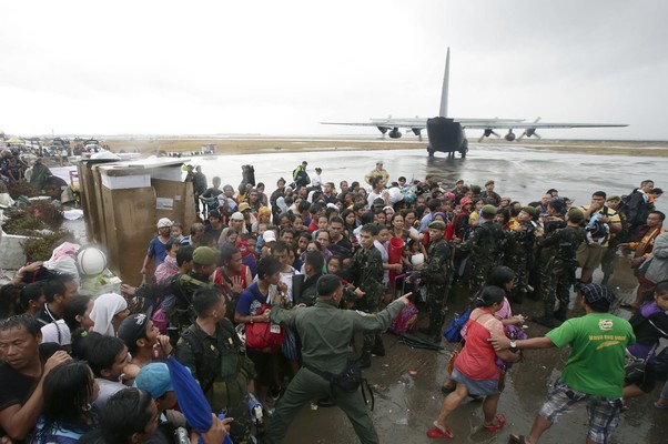 Sobreviventes do tufão Haiyan se aglomeram para embarcar em um avião das Forças Aéreas das Filipinas para saírem da cidade da Tacloban, a mais devastada do país. Autoridades estimam que mais de 10 mil pessoas morreram (Foto: AP Photo/Bullit Marquez)