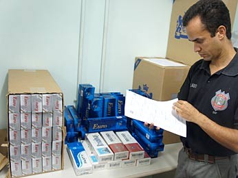 Delegado-chefe da DCPIM Luiz Henrique Sampaio contabiliza o número de caixas de cigarro contrabandeadas (Foto: Ricardo Moreira / G1) Delegado-chefe da DCPIM Luiz Henrique Sampaio contabiliza o número de caixas de cigarro contrabandeadas (Foto: Ricardo Moreira / G1)