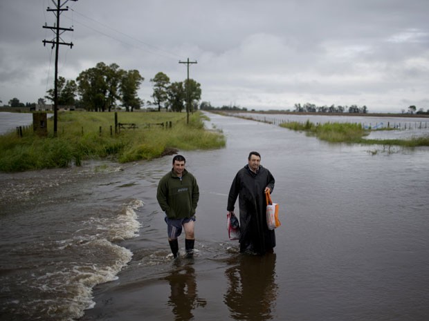 Homens caminham por estrada alagada perto de Carmen de Areco, na Argentina, na segunda-feira (3) (Foto: AP Photo/Natacha Pisarenko)