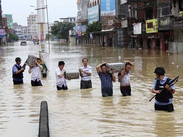 Grupo é forçado a levar dinheiro em caixas por região alagada na China, após pasagem do Tufão 'Utor'. (Foto: Reuters)