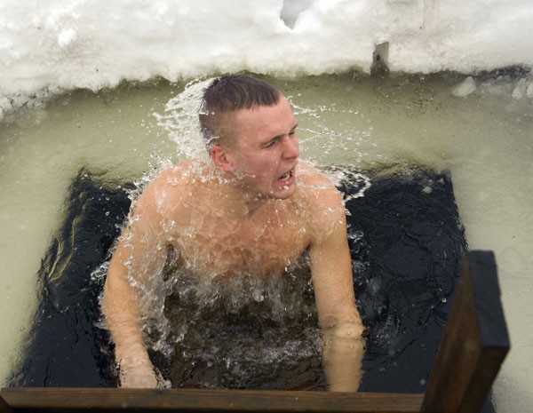 Participante da maratona de saunas entra em buraco de gelo, na Estônia. (Foto: Raigo Pajula/AFP)