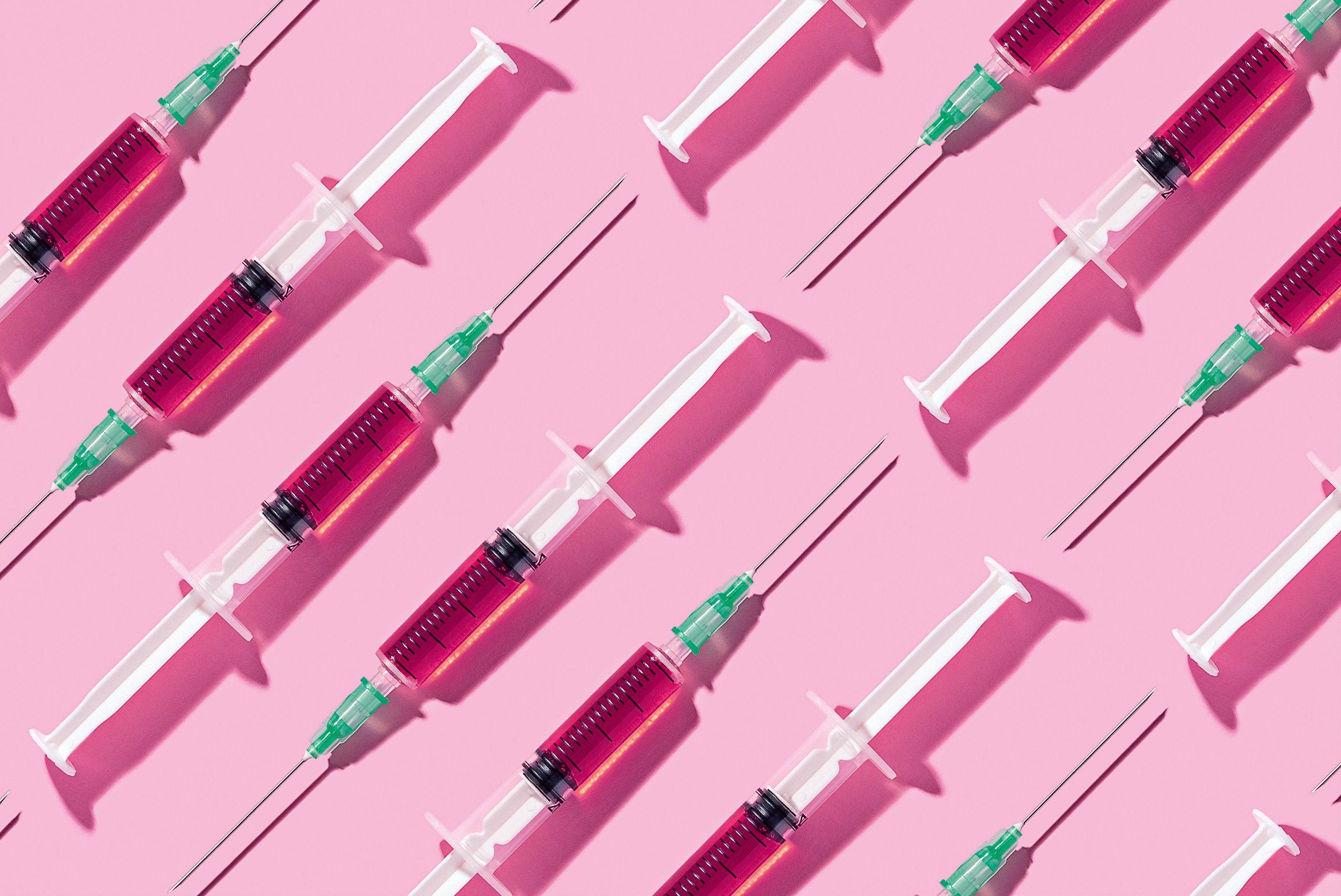 Multiple syringes organized in a pattern over pink background (Foto: Getty Images/Westend61)