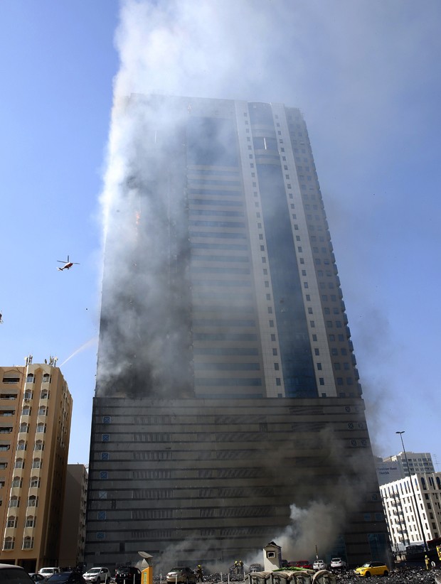 Helicóptero sobrevoa prédio em chamas em Sharjah, nos Emirados Árabes Unidos, na quinta (1º) (Foto: AP Photo)