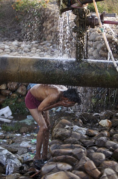 Morador de Jammu, na Índia, toma banho debaixo de tubulação instalada em rua da cidade (Foto: Channi Anand/AP) Morador de Jammu, na Índia, toma banho debaixo de tubulação instalada em rua da cidade (Foto: Channi Anand/AP)
