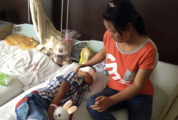 Menino chinês que teve globos oculares arrancados é visto ao lado da mãe nesta quarta-feira (28) (Foto: AP)