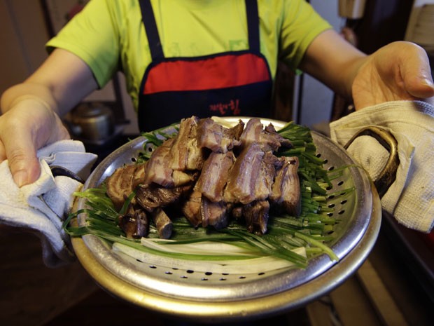 Funcionária mostra prato com carne de cachorro do restaurante Daegyo (Foto: Lee Jin-man/AP)
