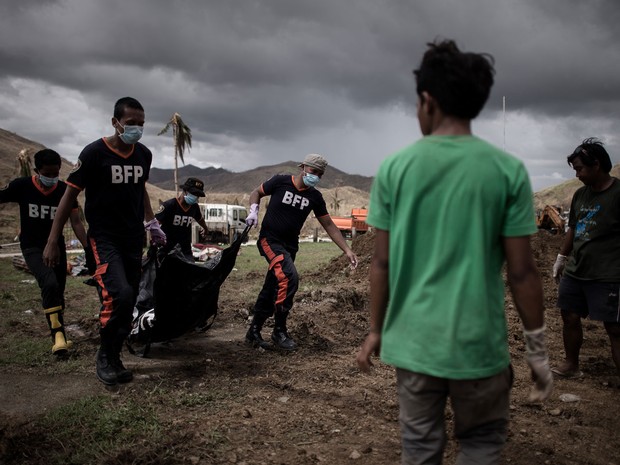 Voluntários carregam corpos de vítimas do supertufão Haiyan para enterro coletivo nesta quinta-feira (14) na região de Tacloban, nas Filipinas (Foto: Philippe Lopez/AFP)