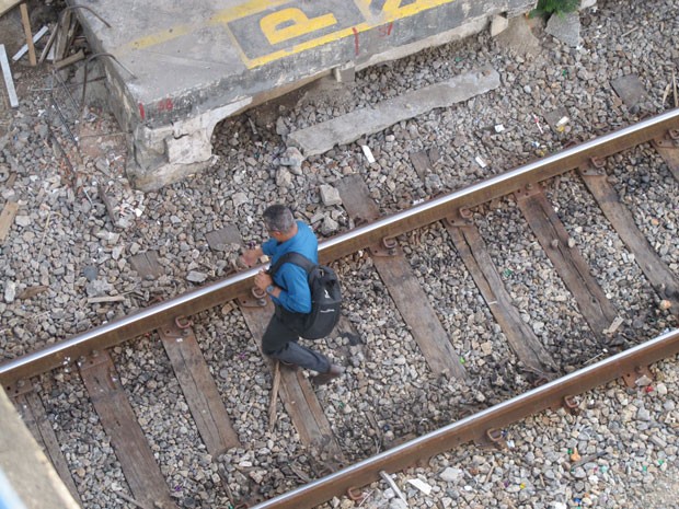 Usuário da SuperVia caminha tranquilamente sobre a linha férrea na estação Triagem (Foto: Marcelo Elizardo/ G1)