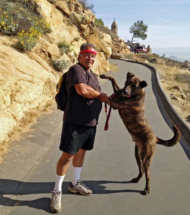 Imagem divulgada pelos bombeiros de Riverside mostra Ramon Llamas e seu cão no monte Rubidoux, na Califórnia. O cachorro de Llamas o ajudou a encontrar um andarilho preso em rochas na última segunda-feira (25), apos aparentemente ter caído. O andarilho estava desidratado, mas consciente.  (Foto: AP)