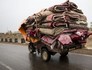Homem conduz triciclo lotado de tapetes (Behrouz Mehr/AFP)