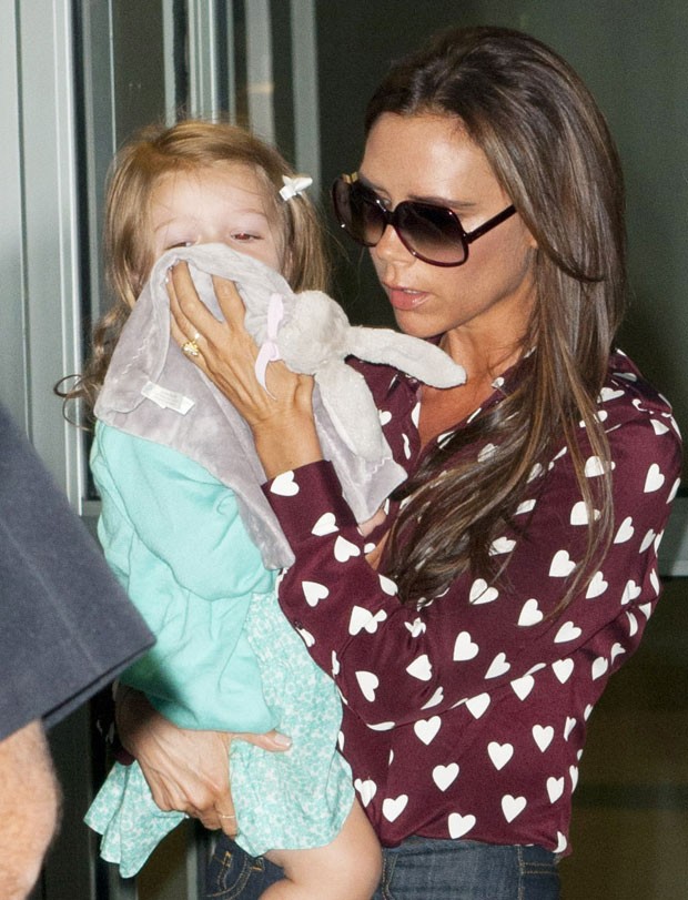 Victoria Beckham esconde o rosto ao desembarcar com a família em