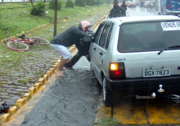 Motociclista ajuda na retirada de um carro que caiu em um buraco em São Vicente, SP (Foto: Angelus Strauss/Arquivo Pessoal)