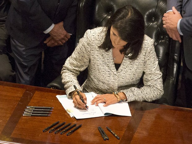 A governadora da Carolina do Sul, Nikki Haley, sanciona lei para remover permanentemente a bandeira da batalha dos confederados do Capitólio do Estado, em Columbia, na quinta (9) (Foto: Reuters/Jason Miczek)