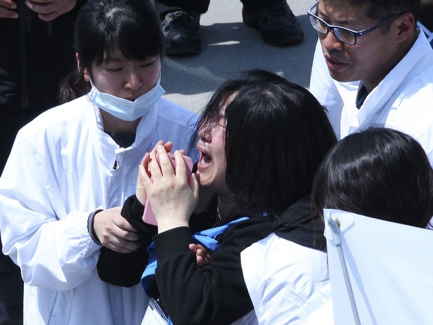 Parente de vítima do naufrágio chora ao ver o nome da filha na lista de mortos no porto de Jindo, na Coreia do Sul (Foto: Yonhap/AP)