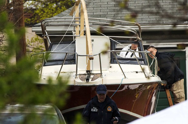 Investigadores inspecionam o barco onde o suspeito do atentado de Boston estava escondido. Embarcação foi removida para  área de armazenamento de evidências (Foto: Lucas Jackson/Reuters)