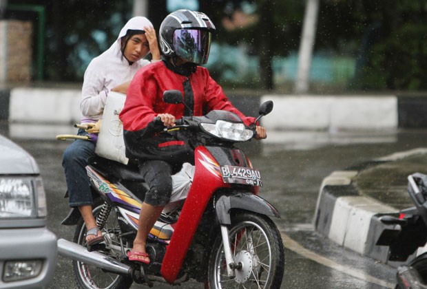 mulher anda na garupa de moto na Indonésia; cidade proibiu que mulheres fiquem de pernas abertas em motos (Foto: AFP)