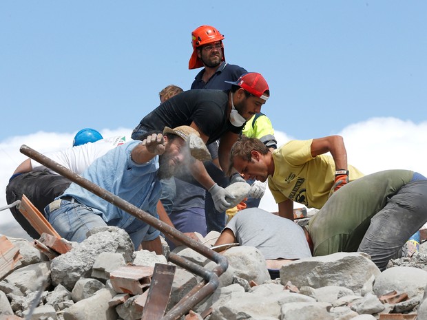 Socorristas usam as próprias mãos para retirar escombros e tentar alcançar vítimas na quarta-feira (24). Trabalhos de resgate prosseguem nesta quinta (Foto: Ciro De Luca/ Reuters)