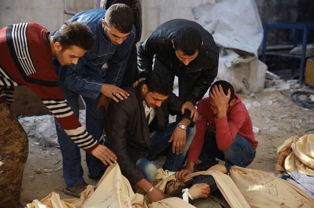 Homens tentam identificar corpos, vítimas do bombardeio que atingiu a cidade de Duma, na Síria (Foto:  ABD Doumany/AFP)
