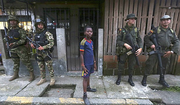 Menino ao lado das Forças Especiais colombianas no bairro de 'La Playita', em Boaventura, durante a visita do ministro da Defesa, Juan Carlos Pinzón. A Human Rights Watch instou autoridades a reforçar a segurança na cidade. (Foto: John Vizcaino/ Reuters) Menino ao lado das Forças Especiais colombianas no bairro de 'La Playita', em Boaventura, durante a visita do ministro da Defesa, Juan Carlos Pinzón. A Human Rights Watch instou autoridades a reforçar a segurança na cidade. (Foto: John Vizcaino/ Reuters)