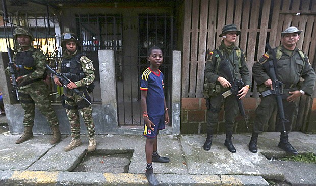 Menino ao lado das Forças Especiais colombianas no bairro de 'La Playita', em Boaventura, durante a visita do ministro da Defesa, Juan Carlos Pinzón. A Human Rights Watch instou autoridades a reforçar a segurança na cidade. (Foto: John Vizcaino/ Reuters)