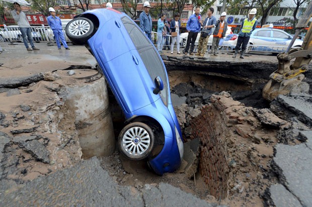 Um motorista escapou sem ferimentos após seu carro cair em uma cratera que se abriu em uma rua da cidade de Lanzhou, na província de Gansu, na China (Foto: Reuters)