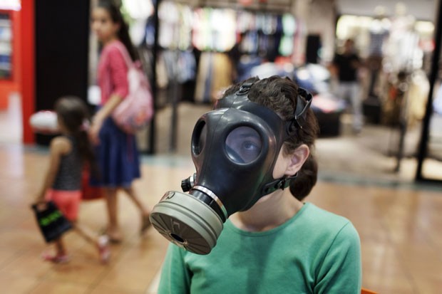 Menina israelense prova máscara de gás em um centro de distribuição em shopping center de Mevaseret Zion, perto de Jerusalém. O governo de Israel começou a distribuir aos moradores kits com máscaras de gás para proteção contra armas químicas e biológicas. (Foto: Menahem Kahana/AFP)