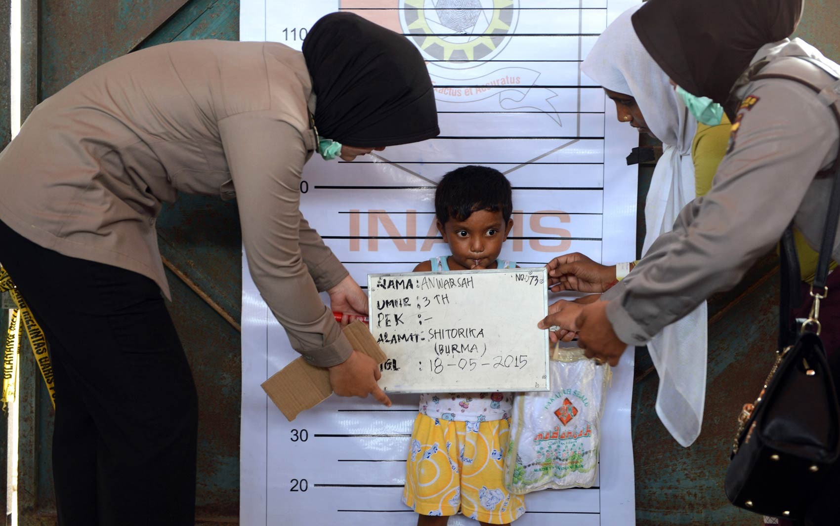 Menino de 3 anos da etnia Rohingya vindo de Mianmar é fotografado para registro em um posto de identificação da polícia da Indonésia no porto de Kuala Langsa, em Aceh. Milhares de Rohingyas migrantes de Mianmar e Bangladesh se refugiaram na cidade (Foto: Romeo Gacad/AFP)