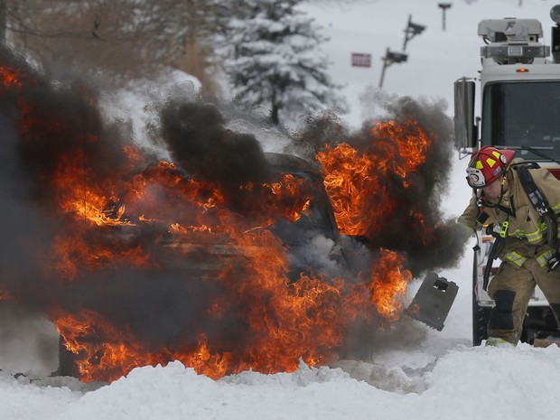 Bombeiro tenta apagar um incêndio em um veículo em Lawrence, Kansas. O carro pegou fogo após tentar atravessar uma montanha coberta de neve. (Foto: Orlin Wagner/AP)