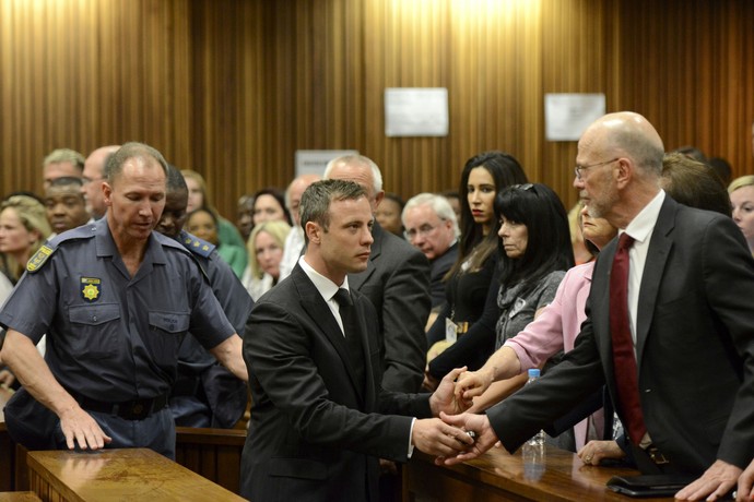 Oscar Pistorius aperta a mão do tio Arnold Pistorius enquanto caminha para ser levado à prisão (Foto: AFP)