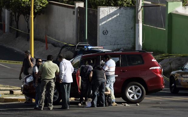 Investigadores e membros da polícia científica observam carro onde o secretário Jose de Jesus Gallegos foi morto a tiros (Foto: Alejandro Acosta/Reuters)