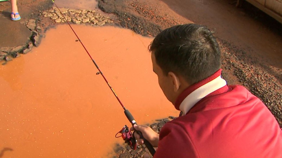Moradores pescam em frente a buraco aberto na zona norte de Ribeirão Preto (Foto: Maurício Glauco/EPTV)