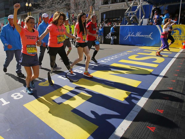 Celeste Corcoran, vítima do atentado de Boston em 2013 quando perdeu as duas pernas, cruza a linha de chegada da maratona com ajuda de familiares nesta segunda (21) (Foto: Brian Snyder/Reuters)