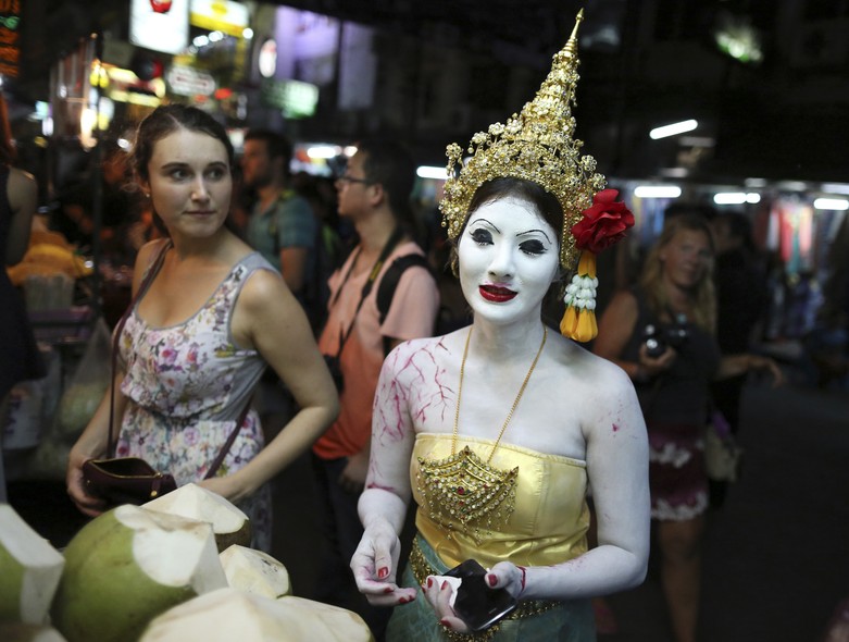 Uma turista observa tailandesa vestida de fantasma para o Halloween em Bangcoc, Tailândia