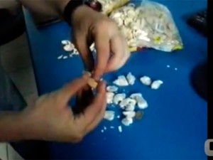 Um a um os pacotes de droga foram colocados entre as camadas das bolachas (Foto: Reprodução/Vídeo cedido ao G1 pela Coape)