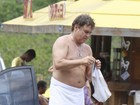Protegido por toalha, Marcos Frota troca de roupa na praia