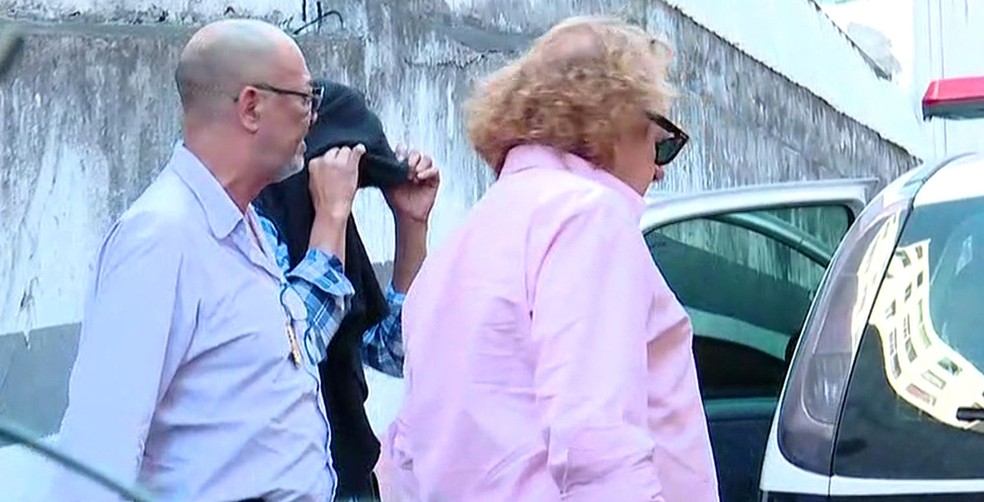Motorista que dirigia veículo que atropelou skatistas na Rua Augusta (com o rosto coberto) se apresenta na delegacia (Foto: TV Globo/Reprodução)