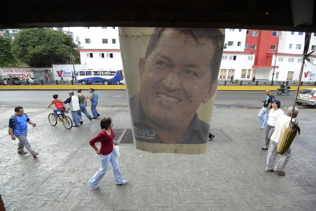 Venezuelanos passam por pôster de Chávez nesta quinta-feira (3) em Caracas (Foto: AFP)
