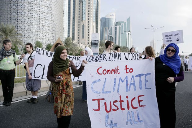 Mulheres seguram cartazes pedindo justiça climática para todos os países (Foto: Osama Faisal/AP)