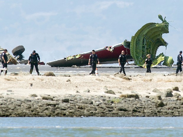 Peritos analisam local onde o Boeing 777, da Asiana Airlines, sofreu um acidente neste sábado (6) ao tentar aterrissar no aeroporto internacional de San Francisco. (Foto: Noah Berger/Associated Press)