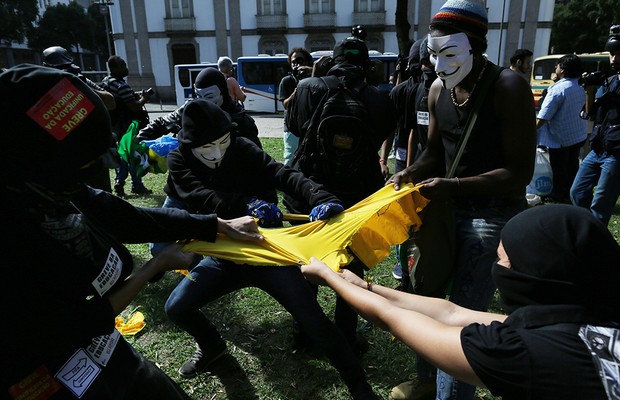 Manifestantes mascarados rasgam camiseta da SELEÇÃO BRASILEIRA em protesto no centro do Rio de Janeiro (Foto: AP Photo/Leo Correa)