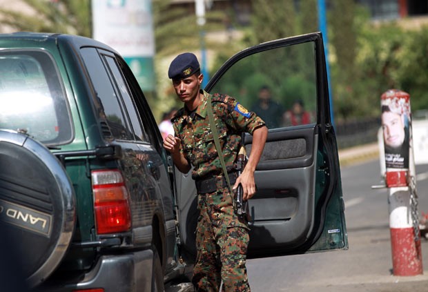 Policial iemenita vasculha carro na entrada do aeroporto da capital, Sanaa, nesta quarta-feira (7) (Foto: AFP)