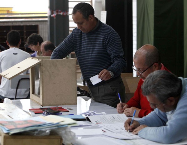 Oficiais contam os votos depois da abertura das urnas em Santiago, no Chile, neste domingo (17).  (Foto: Carlos Vera/Reuters)