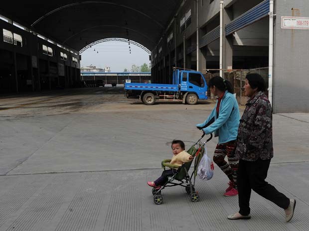 Pedestres passam por mercado de aves fechado pelo risco de transmissão do vírus H7N9 nesta quinta (11) (Foto: AFP/Stringer)