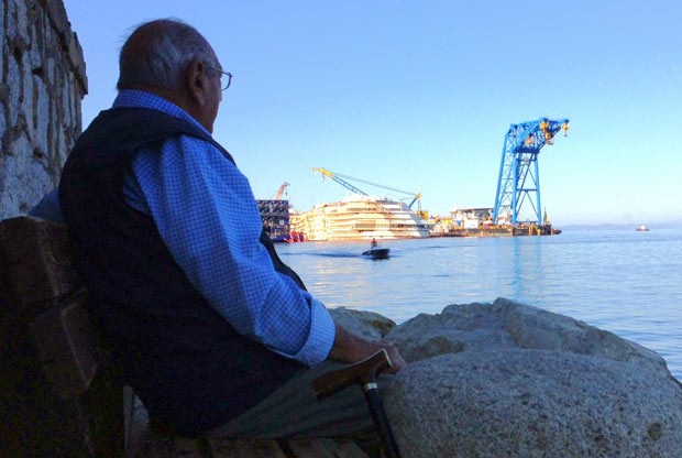 Homem observa, a partir da ilha italiana de Giglio, os trabalhos no naufragado navio Costa Concordia, nesta terça-feira (24) (Foto: AFP)