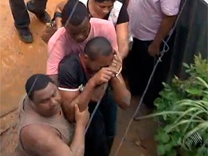 Pai de criança soterrada é amparado por vizinhos, em Salvador, Bahia (Foto: Imagem TV Bahia)