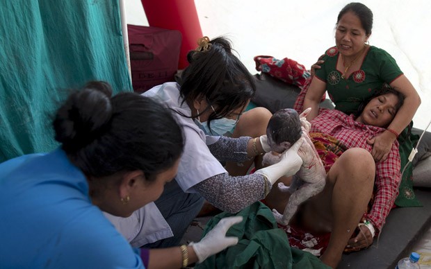 Maya Tamang, de 20 anos, dá à luz uma menina em tenda improvisada do lado de fora do hospital Bhaktapur, no Nepal, após novo tremor causar pânico na população. Hospitais foram esvaziados sob risco de desmoronamento. Parte da foto foi borrada digitalmente (Foto: Athit Perawongmetha/Reuters)