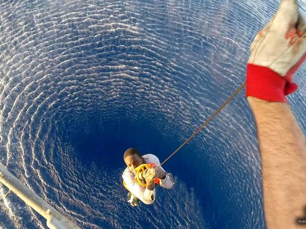 Migrante é içado do mar por um helicóptero da Marinha italiana no local onde um bote afundou no Mar Mediterrâneo. Cerca de 50 migrantes foram dados como desaparecidos depois do naufrágio, informaram as equipes de resgate da Itália (Foto: Reuters/Marinha da Itália)