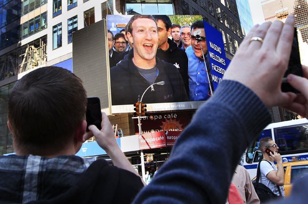 Mark Zuckerberg toca o sino na sede do Facebook na Califórnia e imagem aparece em telão em Nova York, onde ações começam a ser negociadas (Foto: Shannon Stapleton/Reuters)